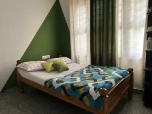 Clean and cozy bedroom with green walls and wooden bed at Astagiri Homestay, Chikmagalur