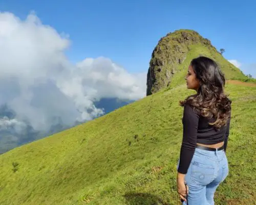 Guest at the Ettina Bhuja peak near Chikmagalur with green hills in view.