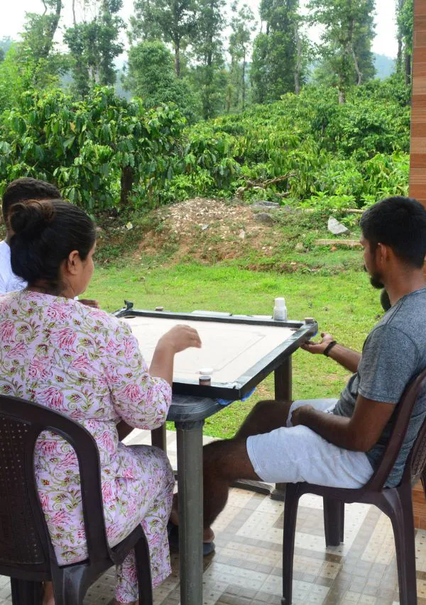 Guests playing carrom with a view of the green coffee estate.