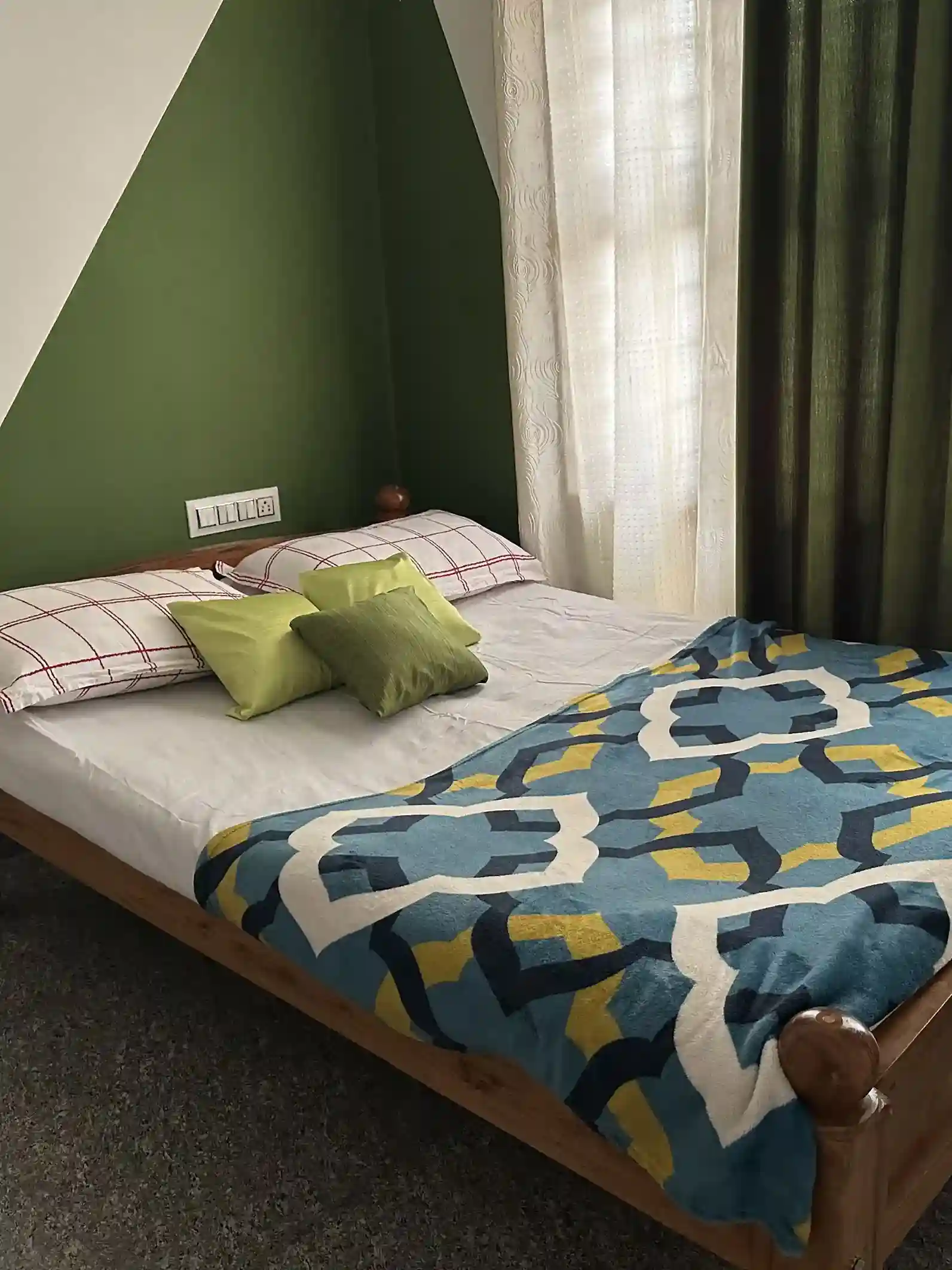 Bedroom with patterned blue bedspread and green wall.