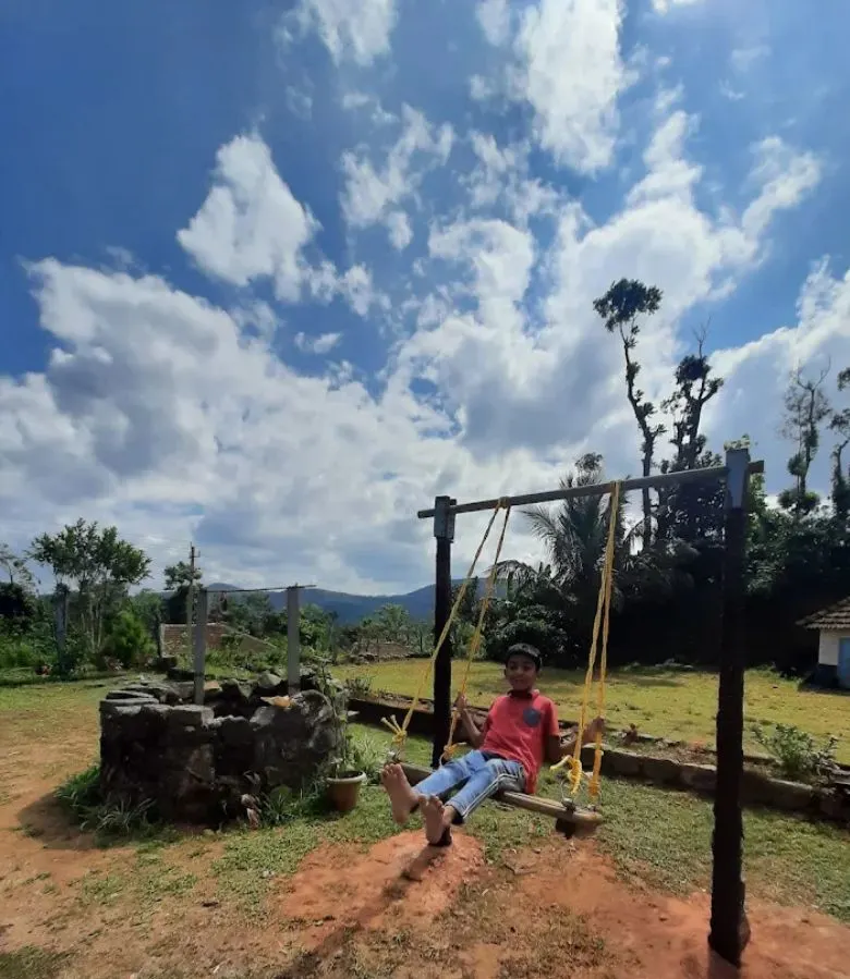 Child on a swing in the open grounds at Astagiri homestay in Chikmagalur.