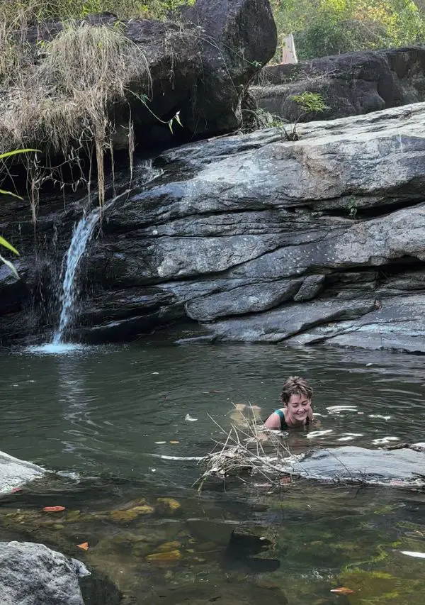 Woman in a natural waterfall pool near Astagiri homestay.