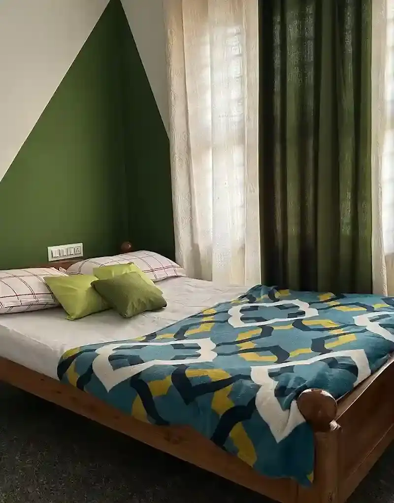 Bedroom with patterned blue bedspread and green wall.