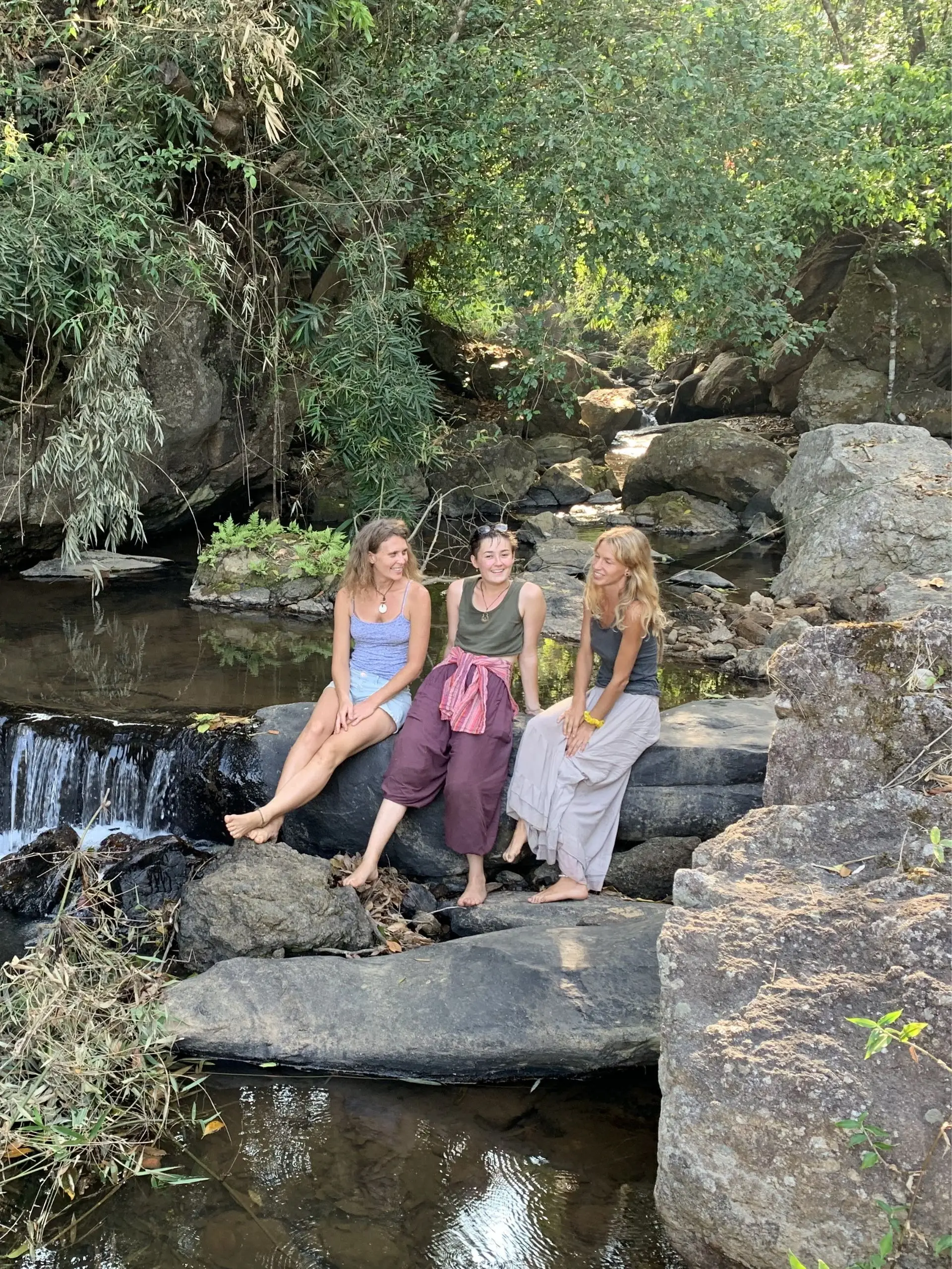 Guests relaxing by a forest stream at Astagiri homestay.