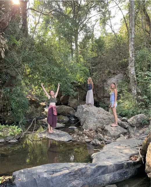 Three guests standing on rocks by a forest stream at Astagiri homestay.